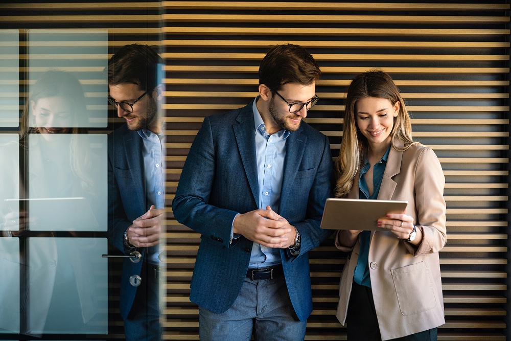 Board admins look at a tablet to discuss how to host an effective startup board meeting.