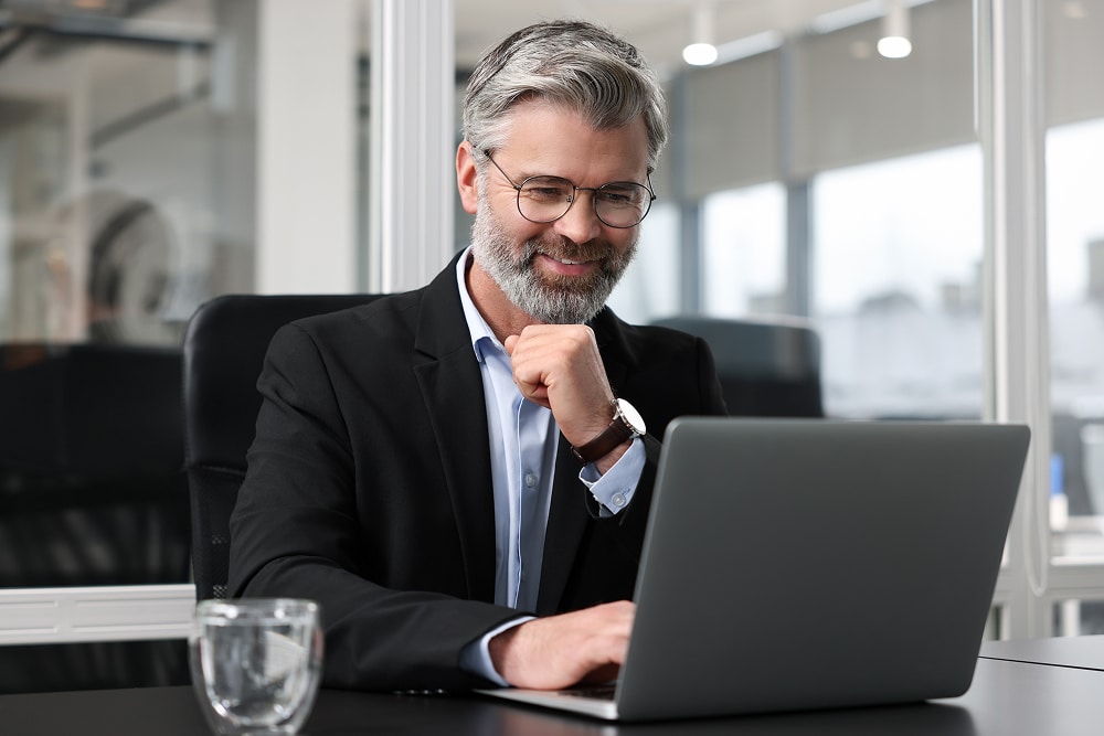 A non-executive director sits at his laptop to review recent board meeting minutes.