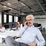 A board member is on the phone sitting at a board table.