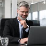 A board member sits at his laptop to draft his board resignation letter.