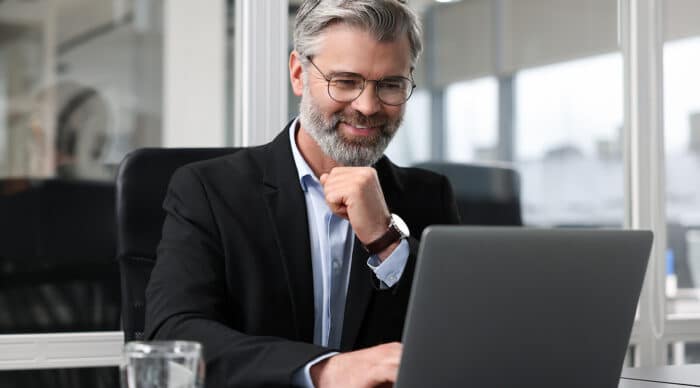 A board member sits at his laptop to draft his board resignation letter.