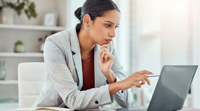 Woman sits at laptop pointing at her screen as she compares top board portals for 2026.