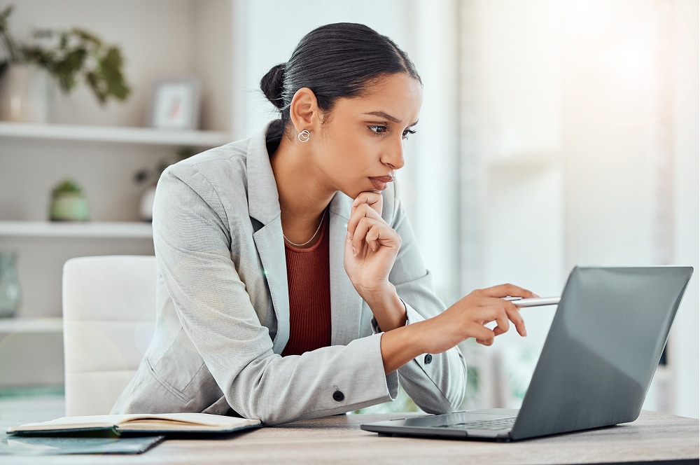 Woman sits at laptop pointing at her screen as she compares top board portals for 2026.
