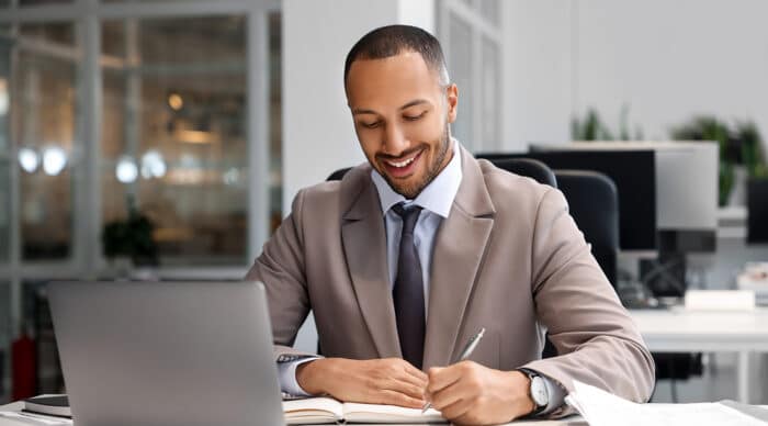 Man sits at desk writing notes as he compares Boardable alternatives.