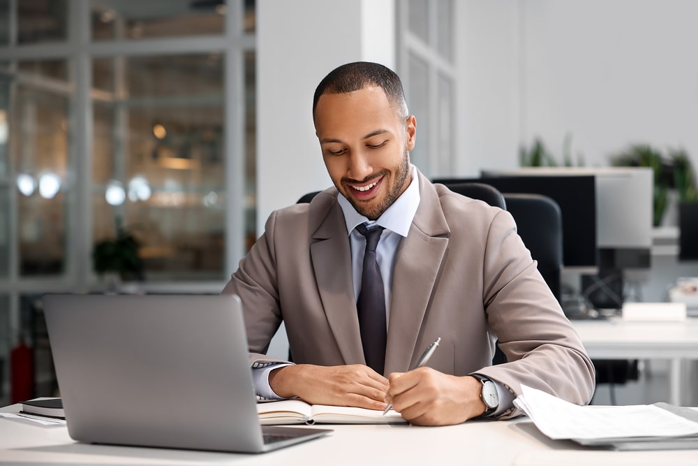 Man sits at desk writing notes as he compares Boardable alternatives.