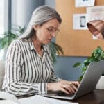 A board director sits at her desk using her laptop to review 501(c)(3) IRS requirements.