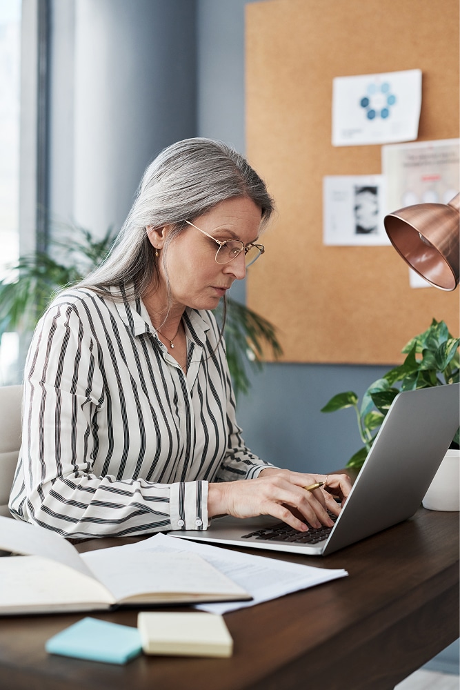 A board director sits at her desk using her laptop to review 501(c)(3) IRS requirements.