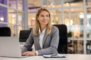 An independent director sits at her desk, using her laptop to review board meeting minutes.