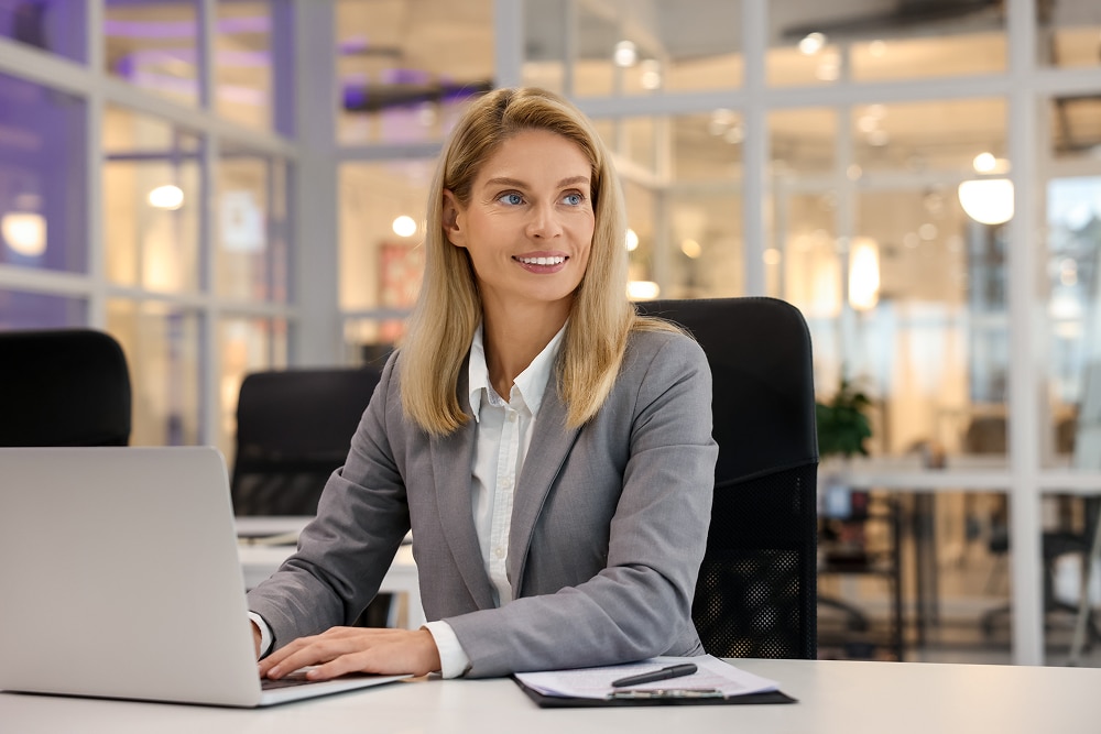 An independent director sits at her desk, using her laptop to review board meeting minutes.