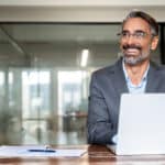 Board director sits at a laptop reviewing how to build a board development plan.