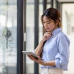 Woman uses her tablet to review a nonprofit board meeting agenda.