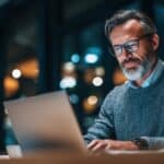 An older board member uses his laptop to access board management software.