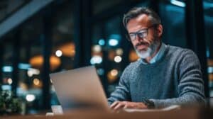 An older board member uses his laptop to access board management software.